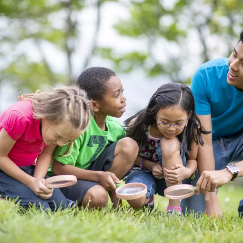 Camp counselor with young children in grass