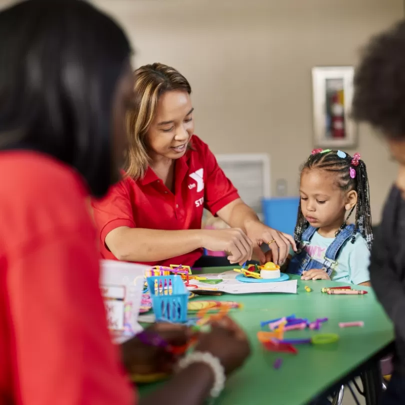 Child sitting at table doing crafts with YMCA childcare provider