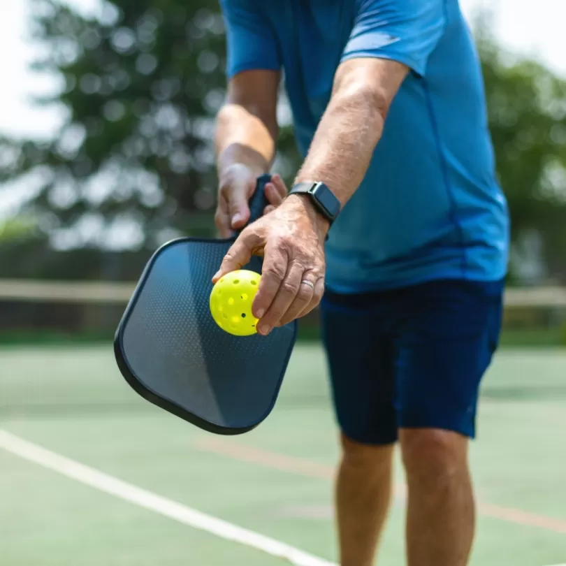 A closeup of a man playing pickleball outside.