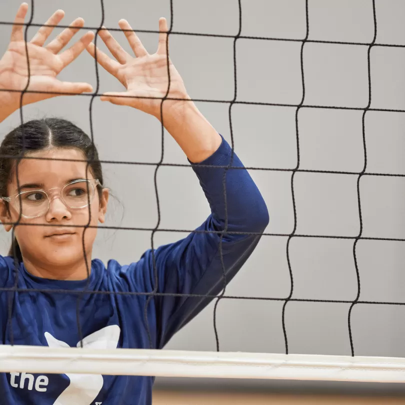 Girl behind volleyball net.