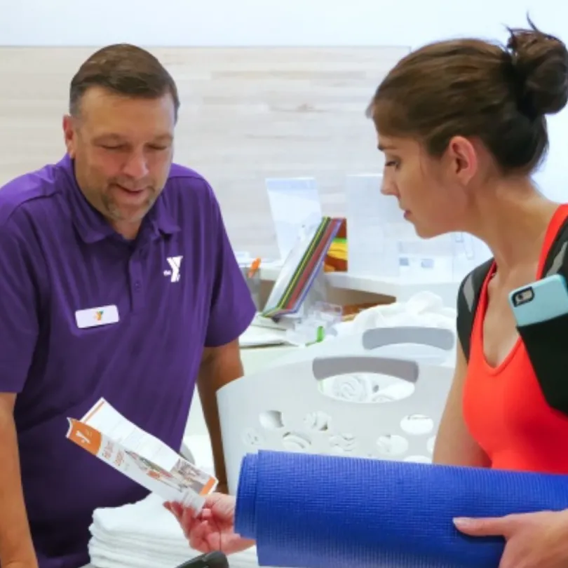 A membership engagement representative helps a member at the front desk.