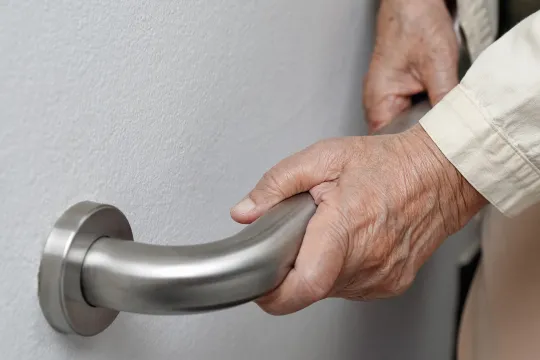 A pair of hands hold on to a staircase railing for support.