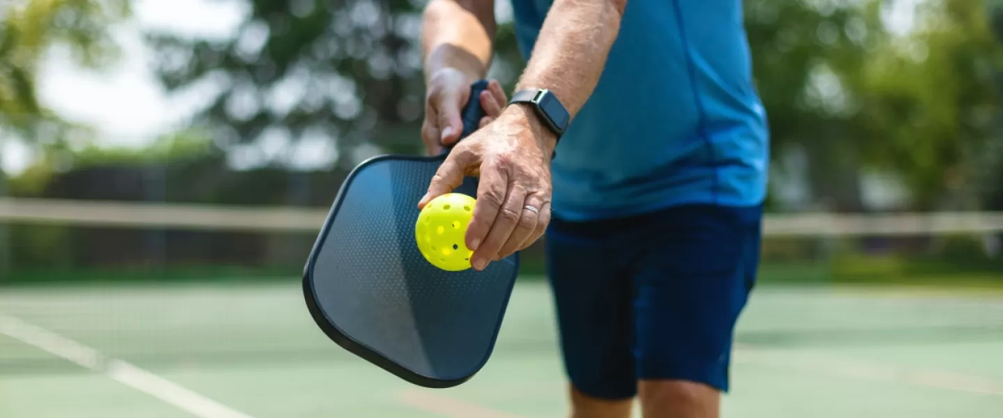 A closeup of a man playing pickleball outside.