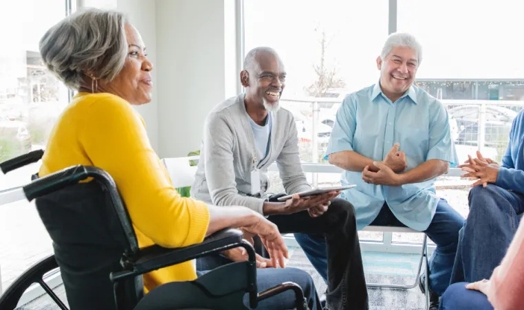 A group of older adults sit and discuss during a support group.