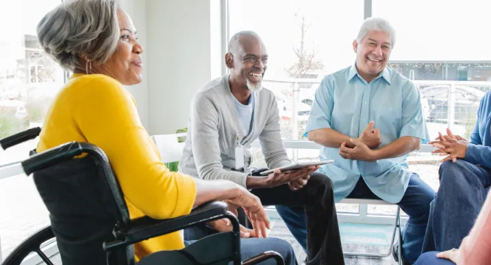 A group of older adults sit and discuss during a support group.