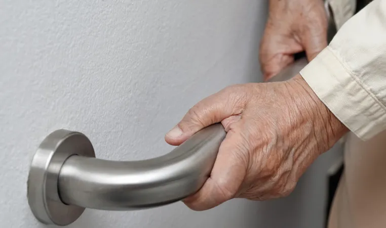 A pair of hands hold on to a staircase railing for support.