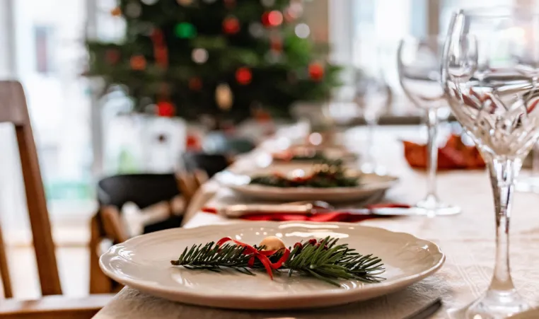 A close up of a holiday dinner place setting with decorations in the background.